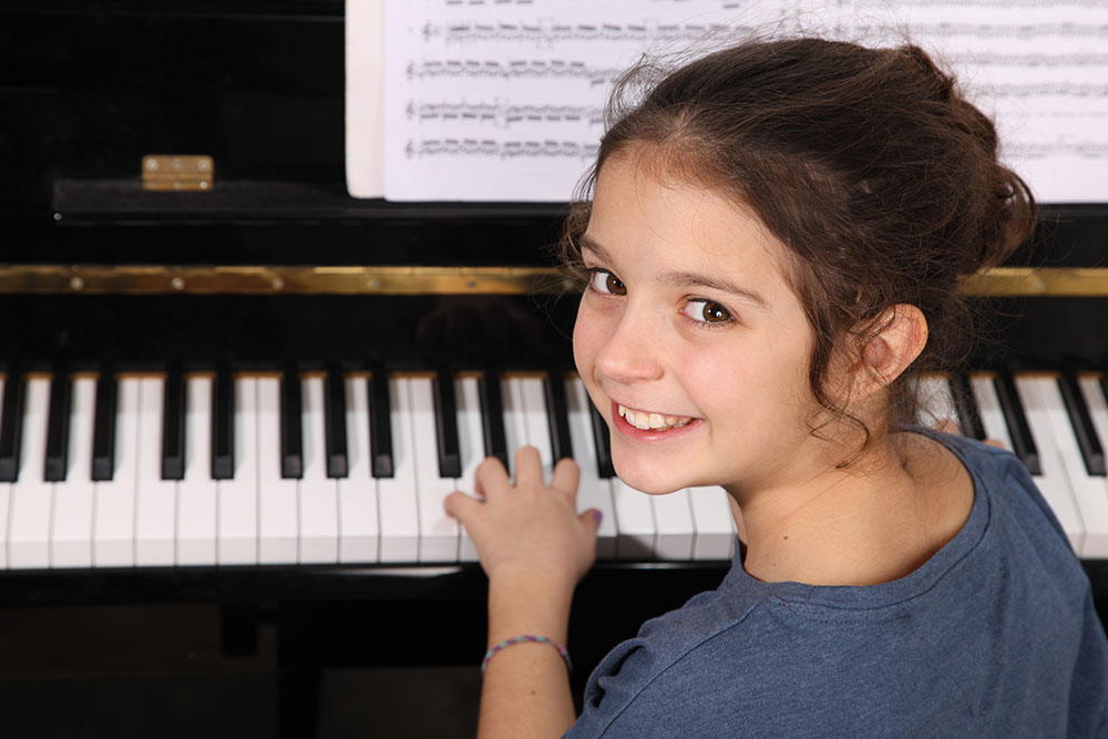 Das Bild der Musikschule Odenwald zeigt ein kleines Mädchen am Klavier